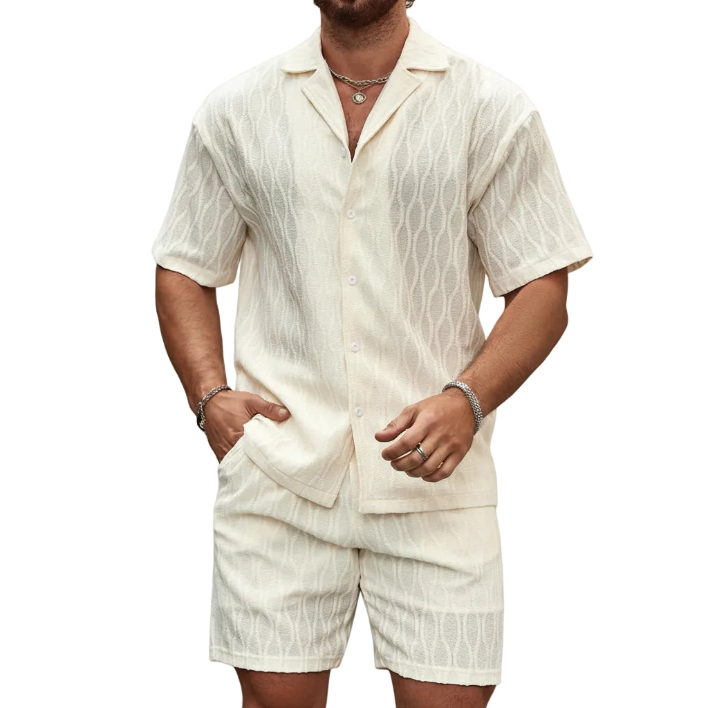 Man wearing a white textured shirt and shorts set against a stone wall.